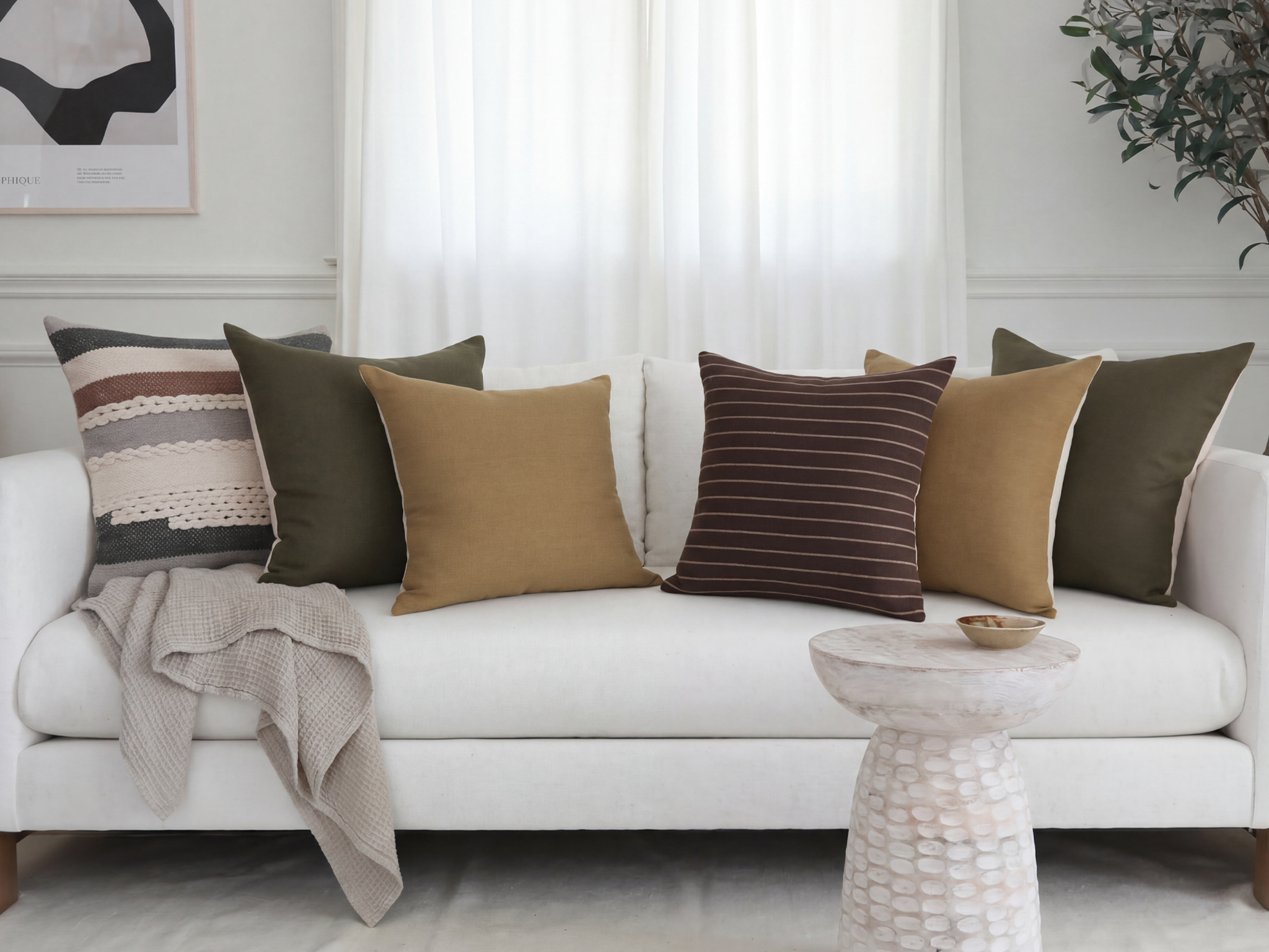 Crosby striped textured, olive linen, ochre linen, and umber striped wool pillow covers styled together on a cream sofa with a grey throw blanket
